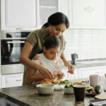 A mom and daughter share a bonding moment while preparing a healthy lunch together in the kitchen.