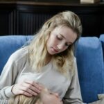 A mother tenderly cares for her ill child on a couch, demonstrating comfort and family love.