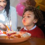A joyful birthday celebration with a child blowing out candles surrounded by family, capturing a happy moment.