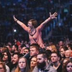 A woman joyfully cheers amidst a lively concert crowd, exuding energy.